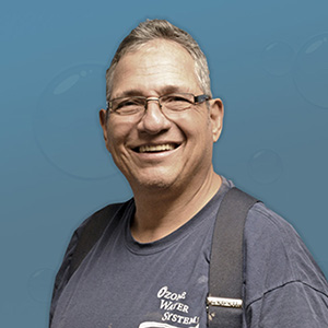 Smiling middle-aged man in glasses against a blue background.